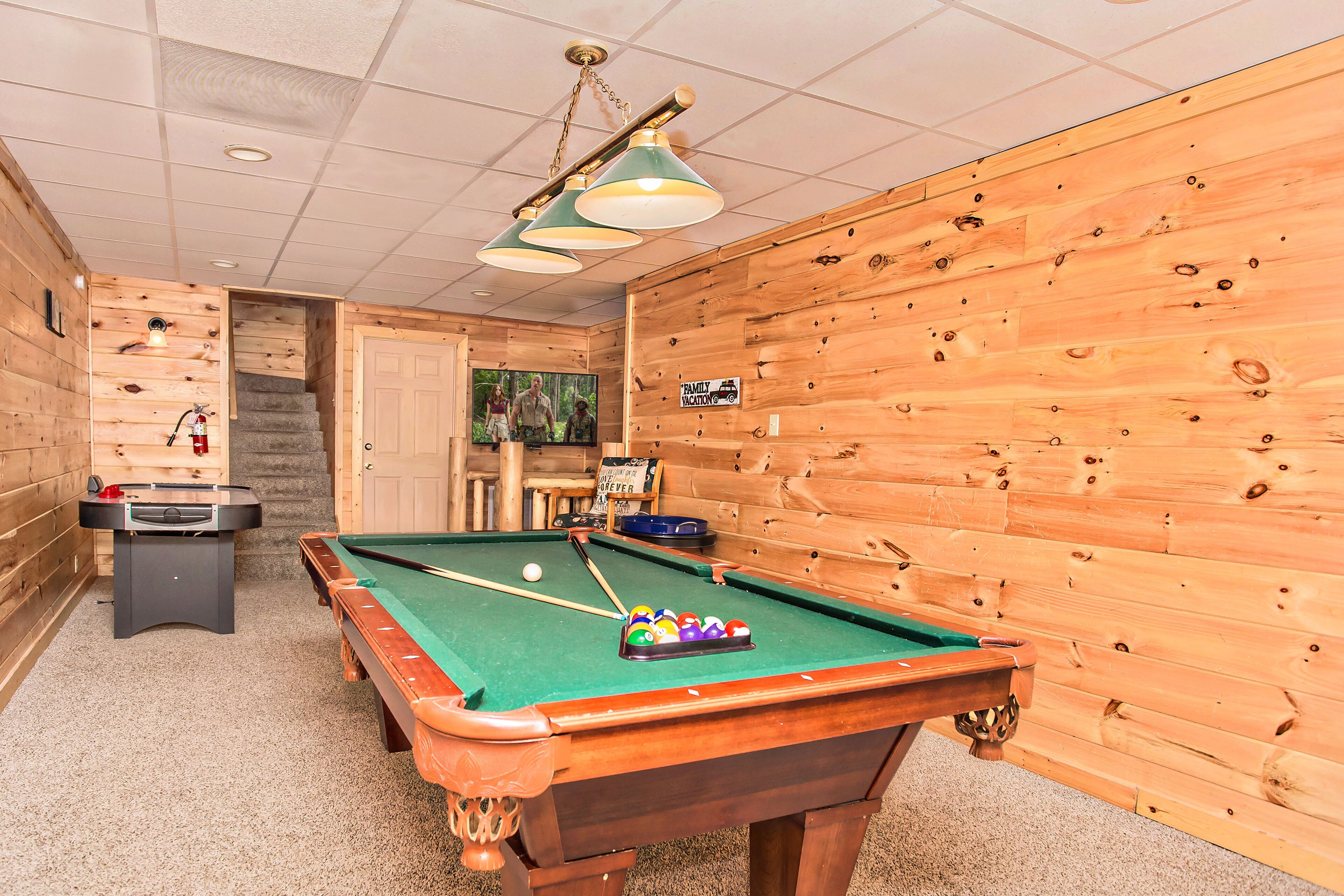 Une table de billard recouverte d’un drap vert, une table de baby-foot et un panneau indiquant un espace réservé aux familles en vacances.