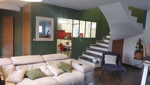 A living room with a sofa, a chair, and a staircase leading to an upper floor.