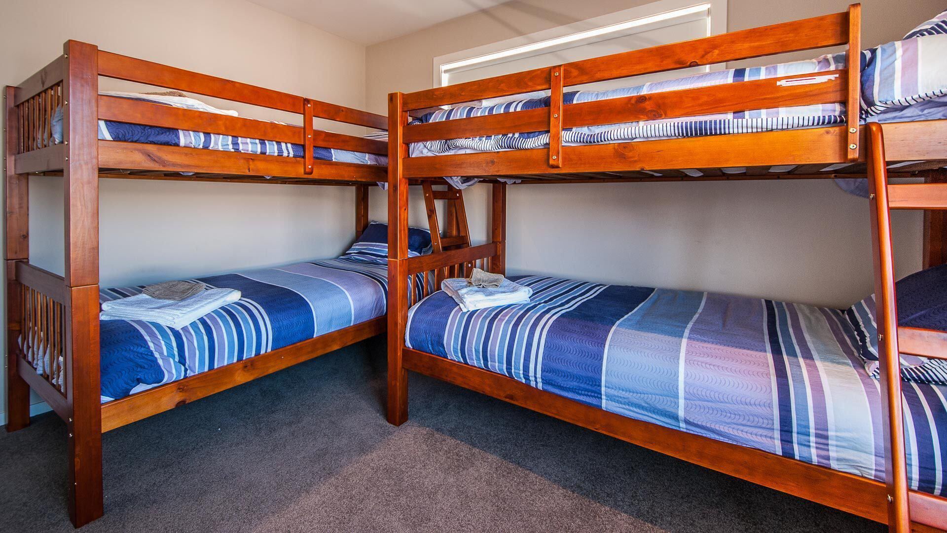 A room with two bunk beds, each with a striped blue and white bedspread.