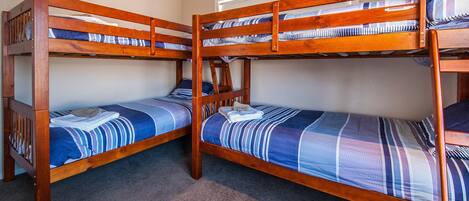 Ein Zimmer mit zwei Etagenbetten, jeweils mit einer blau-weiß gestreiften Bettdecke.