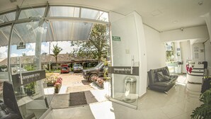A hotel lobby with a glass entrance, a reception desk, a sofa, and a trash bin. - Llanogrande Airport by Bernalo Hotels (Rionegro)