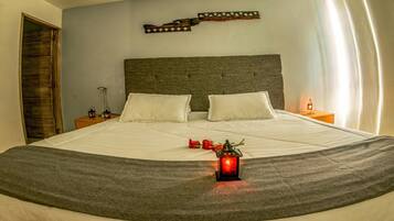 A neatly made bed with white linens, a grey throw blanket, and a decorative lantern on the bed.