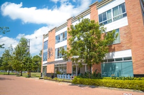 A modern building with a brick facade, large windows, and outdoor seating area. - Llanogrande Airport by Bernalo Hotels (Rionegro)