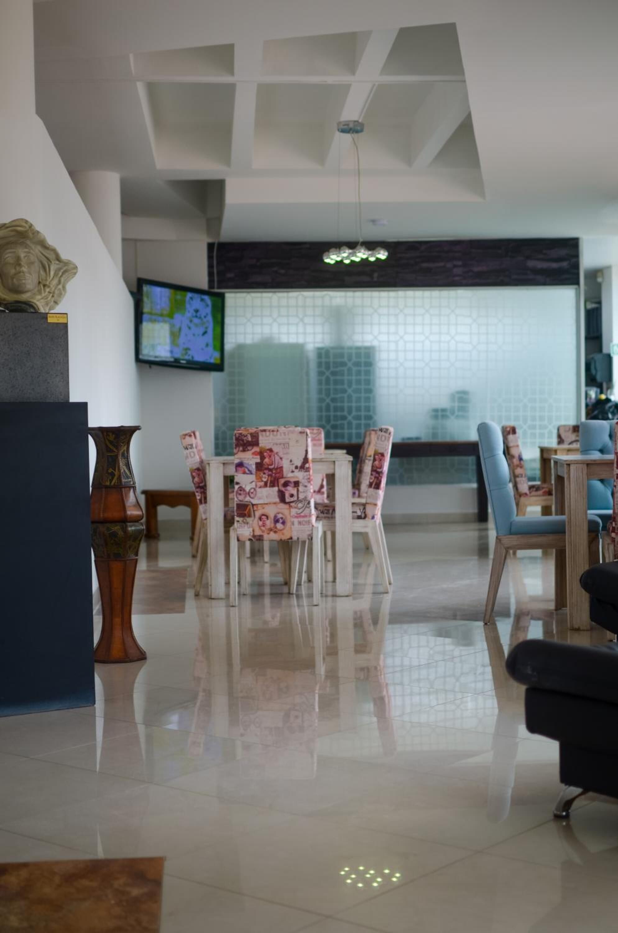 A modern dining area with a central table, chairs, and a television mounted on the wall.