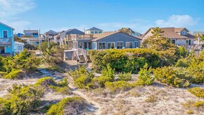 A coastal residential area with houses featuring balconies and a sandy landscape with sparse vegetation. - Oceanfront Dog Friendly Cottage in Avon with Grill and Screened Porch (Avon)