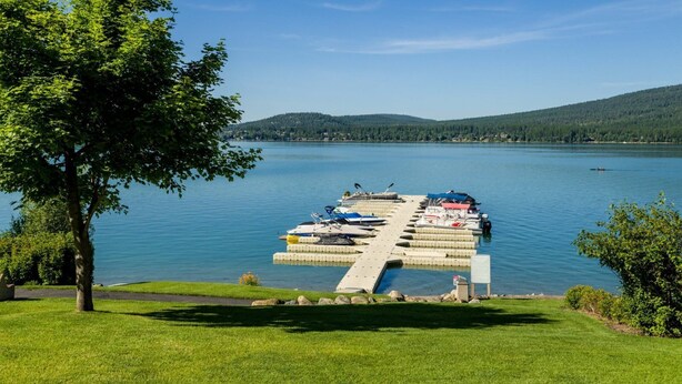 A dock with boats, a grassy area, and a lake with hills in the background.