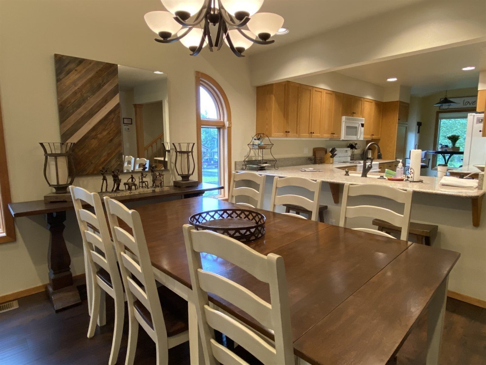 A modern kitchen with wooden cabinets, a central island, and white chairs.