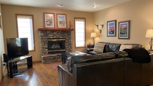 A living room with a stone fireplace, leather sofa, and a television.