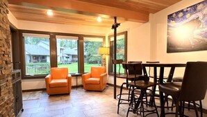 Una habitación amplia con chimenea, ventanas grandes y un comedor con sillas y una mesa.