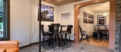 A dining area with a wooden ceiling, a painting on the wall, and a fireplace.