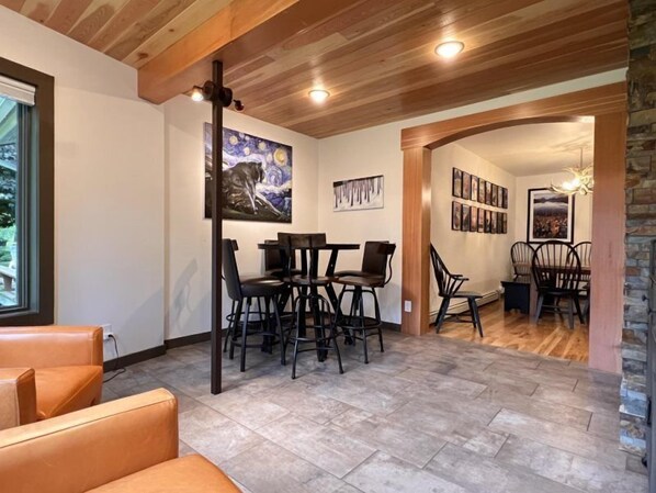 A dining area with a wooden ceiling, a painting on the wall, and a fireplace. - Mountain Harbor #143 3 Bedroom Condo (Whitefish)