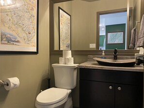 A bathroom with a toilet, sink, and a framed map on the wall. - Mountain Harbor #143 3 Bedroom Condo (Whitefish)