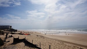 A beach with a building on the left, sandy beach, and ocean. - Joli Appartement avec terrasse face à l'océan (016) (Biscarrosse)