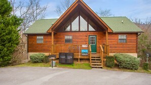 A log cabin with a green door, a wooden porch, and a chimney. - 🌲Dancing Bear Den🌄Mountain Views, Resort Pool & Hot Tub (Sevierville)