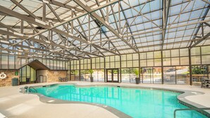 An indoor swimming pool with a glass ceiling, surrounded by a concrete floor and a brick wall. - 🌲Dancing Bear Den🌄Mountain Views, Resort Pool & Hot Tub (Sevierville)
