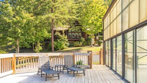 A wooden deck with outdoor furniture, a glass-enclosed area, and a view of a building with a wooden deck and a pergola. - 🌲Dancing Bear Den🌄Mountain Views, Resort Pool & Hot Tub (Sevierville)