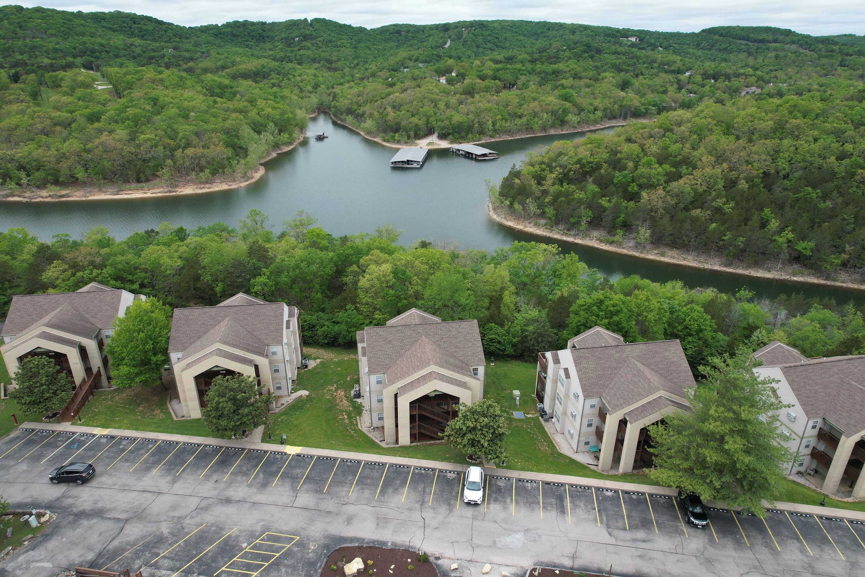 A residential area with a river, a parking lot, and houses with a central building.