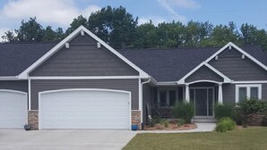 A two-story house with a front garage and a well-maintained lawn. - Close to Aquatic Center, Horicon Marsh, Wedding Venue, Easy Drive to EAA (Waupun)