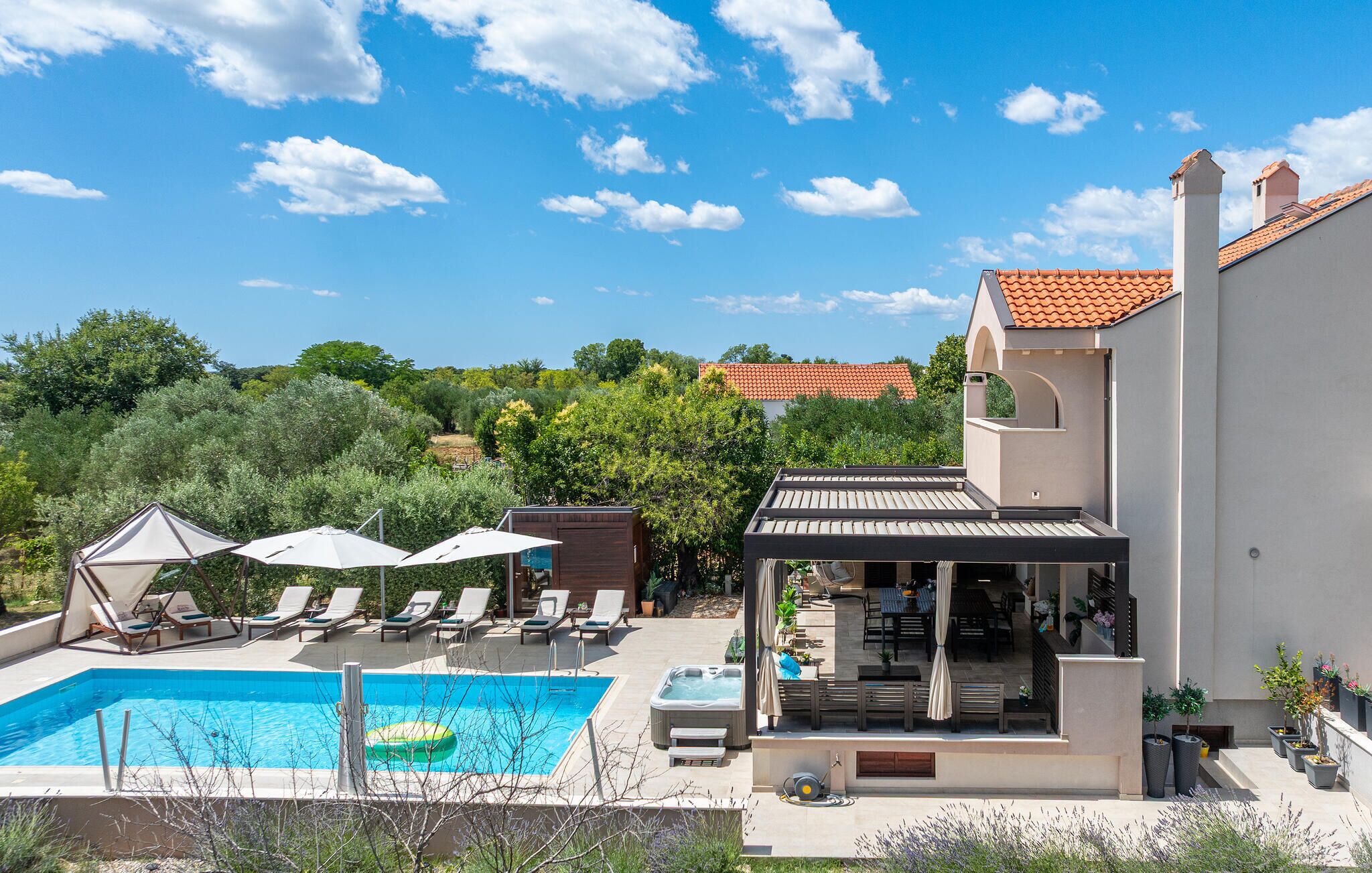 A modern villa with a swimming pool, outdoor seating, and a patio area.