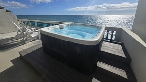 Un jacuzzi en una terraza de madera con vista al océano.