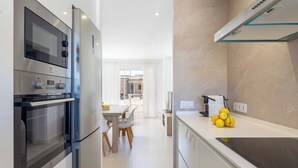 Una cocina moderna con electrodomésticos de acero inoxidable, un comedor con mesa y sillas, y vistas al salón de comidas.