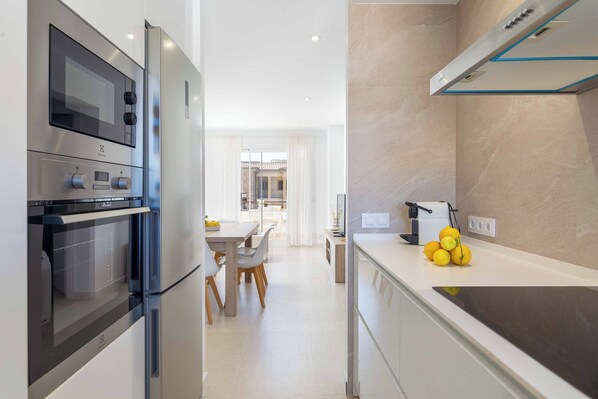 A modern kitchen with stainless steel appliances, a dining area with a table and chairs, and a view into the dining room.