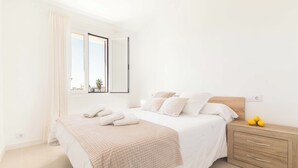 Un dormitorio con una cama, una mesita de noche, un espejo y una ventana.