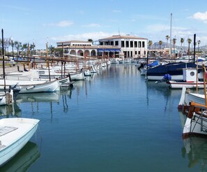 A marina with several boats docked, a building with arches, and a clear sky. - Apartamento La Llimona - Nice apartment near the beach in Port de Pollença (Port de Pollença)