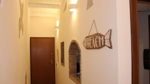 Un pasillo con una puerta de madera, un letrero con forma de pez y un arco de ladrillo.