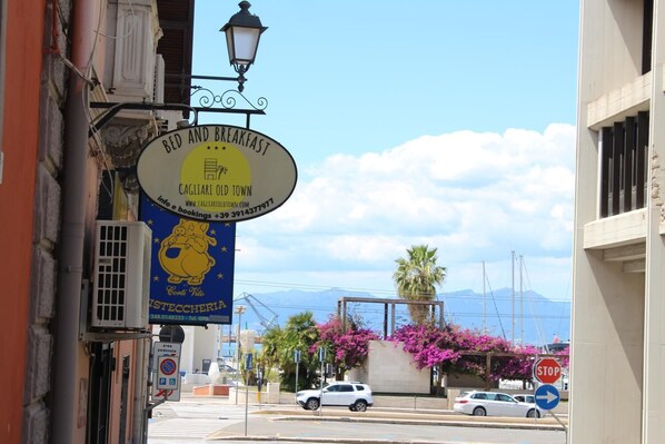 Vista de la calle con un letrero de 'Bed and Breakfast Cagliari Old Town' y un banner de 'ISTECCHERIA'.