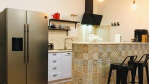 Una cocina moderna con un refrigerador de acero inoxidable, un horno empotrado, una cafetera y un salpicadero con diseño.