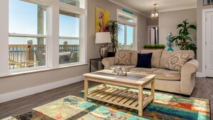 A living room with a beige sofa, a wooden coffee table, and a colorful rug. - Gulf Front, Private Heated Pool, Pet Friendly, 2 Master Suites! – Island Time IV (Dauphin Island)