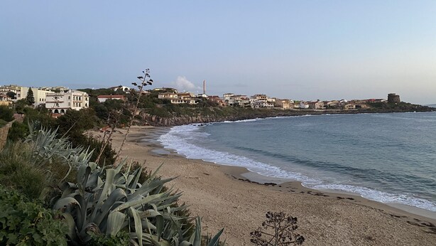 Une ville côtière avec une plage, des bâtiments et un phare.