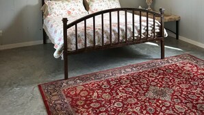 Ein Schlafzimmer mit einem Bett, einem Deckenventilator, einer Klimaanlage, einem Teppich und zwei gerahmten Bildern an der Wand.