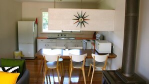Una cucina compatta con isola centrale, mobili bianchi e un decorativo pannello a forma di esplosione.