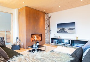 Ein modernes Wohnzimmer mit Kamin, Wandfernseher und Bücherregal.