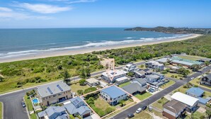 Luchtbeeld van een kustgebied met woningen, een weg en een strand.