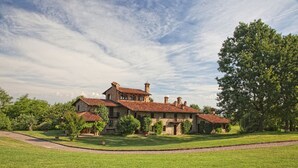 Ein großes, historisches Steinhaus mit mehreren Schornsteinen und einem gepflegten Rasen.