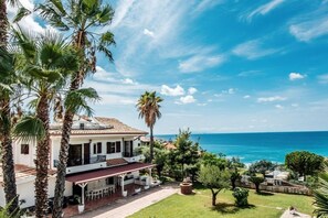 A coastal house with a patio, palm trees, and a view of the sea. - Villa Anna, for 10/13 people, with private pool and near the beach (Ricadi - Capo Vaticano)