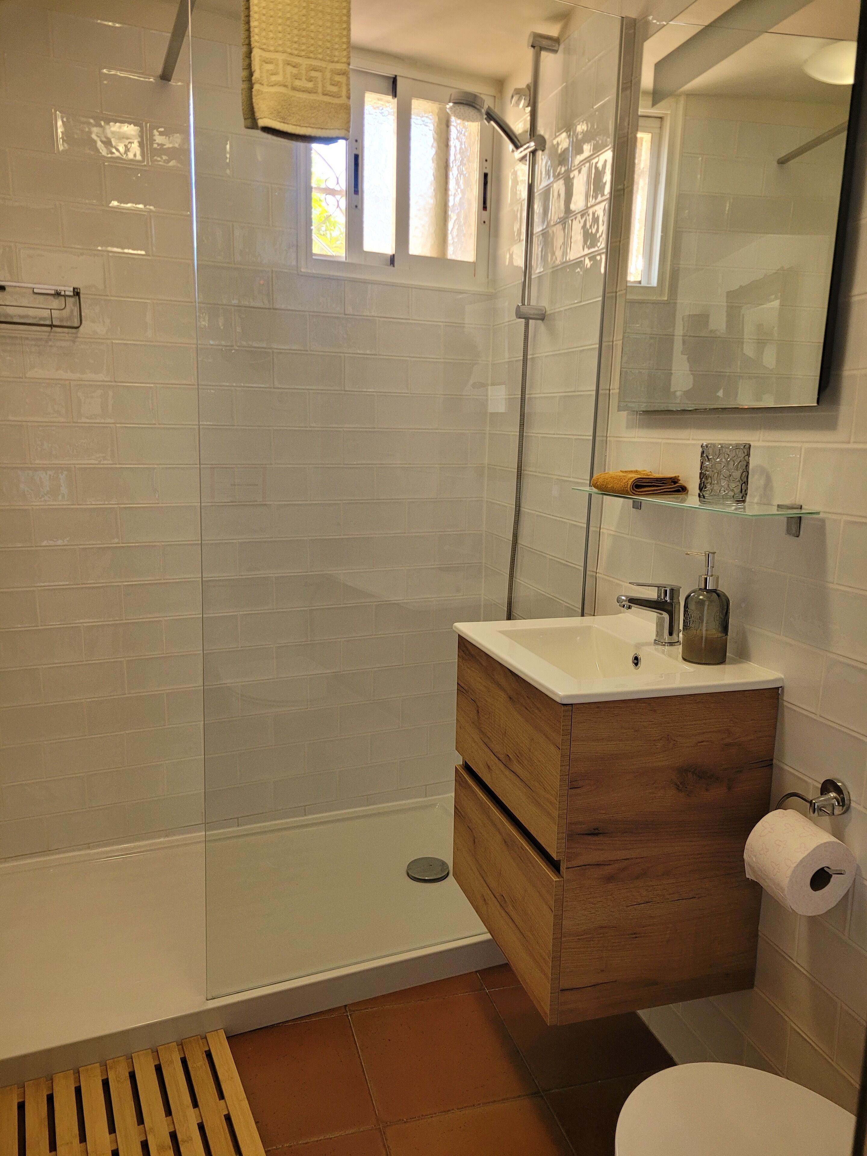 A bathroom with a glass shower enclosure, a wooden vanity with a sink, and a toilet.