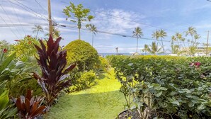 Ein Garten mit vielfältigen Pflanzen, einer ordentlich geschnittenen Hecke und Blick auf das Meer.
