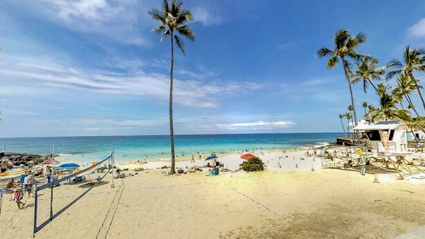 Ein Strand mit Palmen, sandigem Ufer und blauem Himmel.