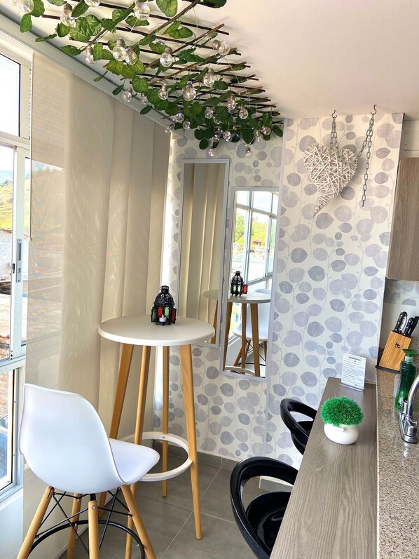 A modern kitchen with a round white table, a white chair, and a small potted plant on the counter.