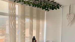 Et moderne værelse med et rundt bord og to hvide stole, en hængende plante og en hjerteformet dekoration på væggen.