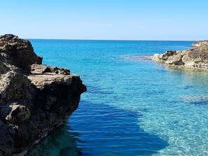 A coastal scene with clear blue water and rocky formations.