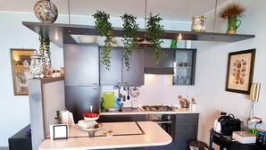 Una cuina moderna amb una illa central, tamboretes de bar, plantes penjants i diversos electrodomèstics.