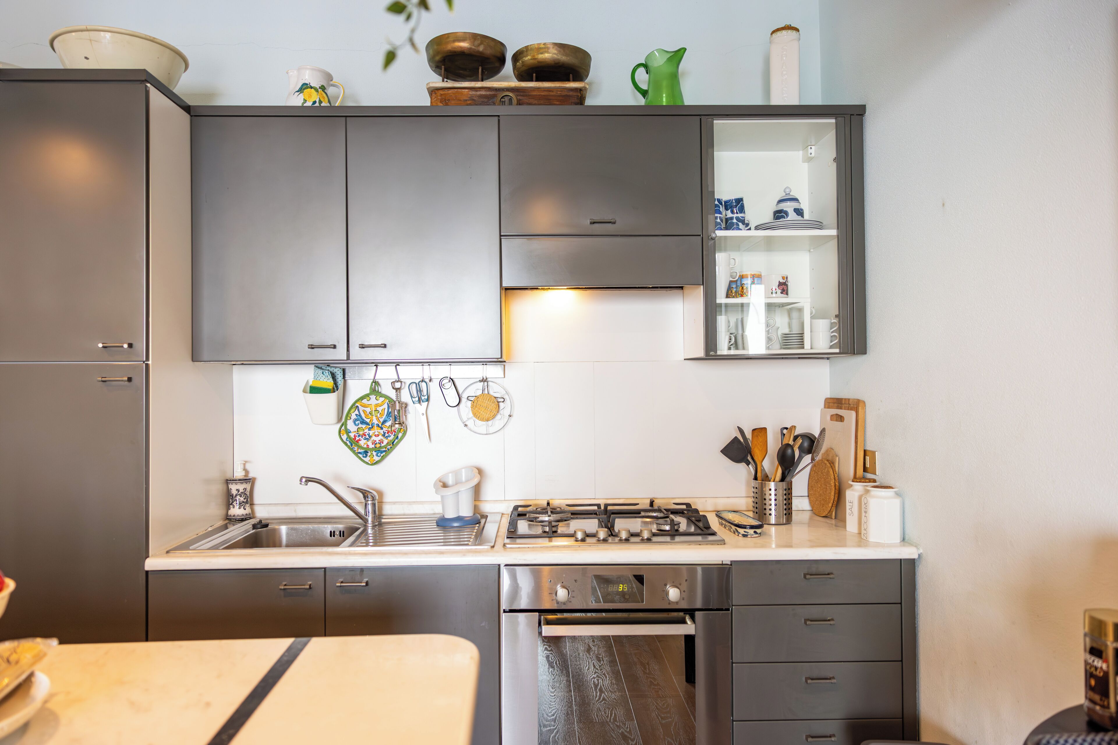A modern kitchen with grey cabinets, a stainless steel sink, and a gas stove.