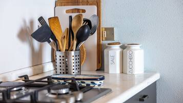 Una encimera de cocina con un portalapices, una estufa y dos recipientes con la etiqueta 'SALE' y 'ZUCCHERO'.