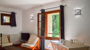 A room with a sofa, a table with cups, a TV, and a window with curtains.