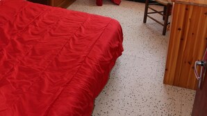 Quarto com cama, cómoda de madeira, secretária e cadeira.